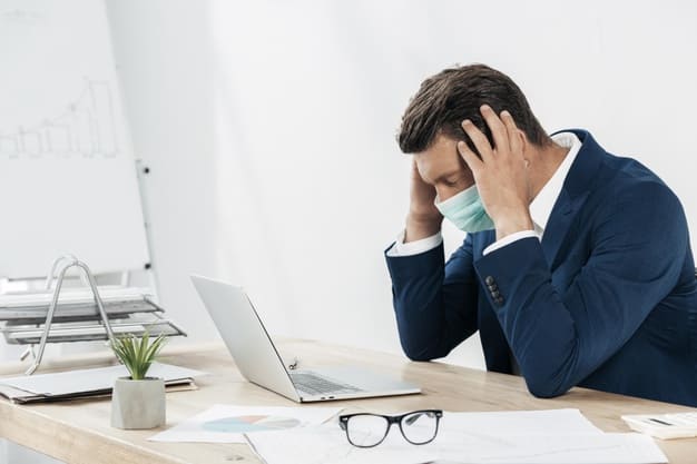 Inadimplência de consumidores reduziu mas falência nas empresas volta a crescer. Funcionário sentado na frente do computador com mãos na cabeça